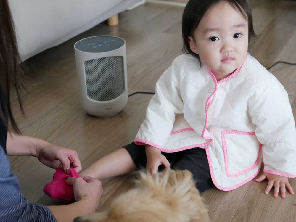 子供がデュクスのミニヒーターの近くで快適に座る姿