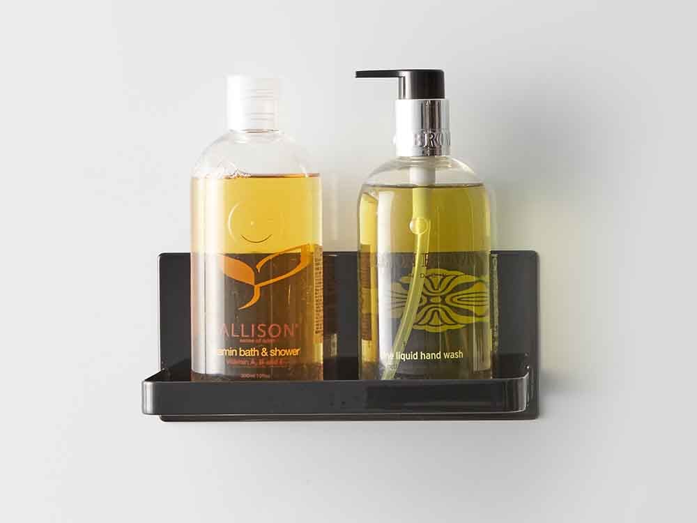 YAMAZAKI/towerのマグネットバスルームラックにガラス製の香水ボトルとソープディスペンサーが配置されている様子