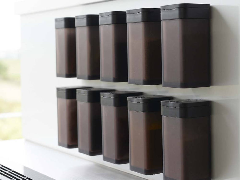 棚に置かれた黒色のタワーマグネットスパイスボトルとプラスチック保存容器