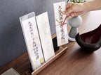 RIN/リンの神札スタンド。スチールと天然木積層合板製で、紙や箸などのキッチン用品が置かれている様子。