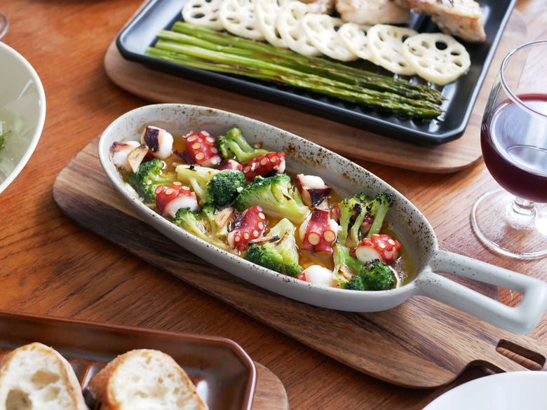 IBUKICRAFTの耐熱陶器製グリルプレートに新鮮な野菜とサラダが盛られ、食器とともに食卓に配置された様子