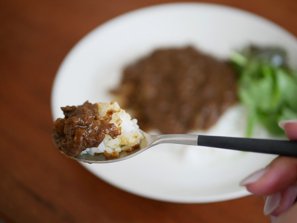 Cutipol MIO ブラックシルバーのカトラリーセットと白ご飯を使った食卓の写真