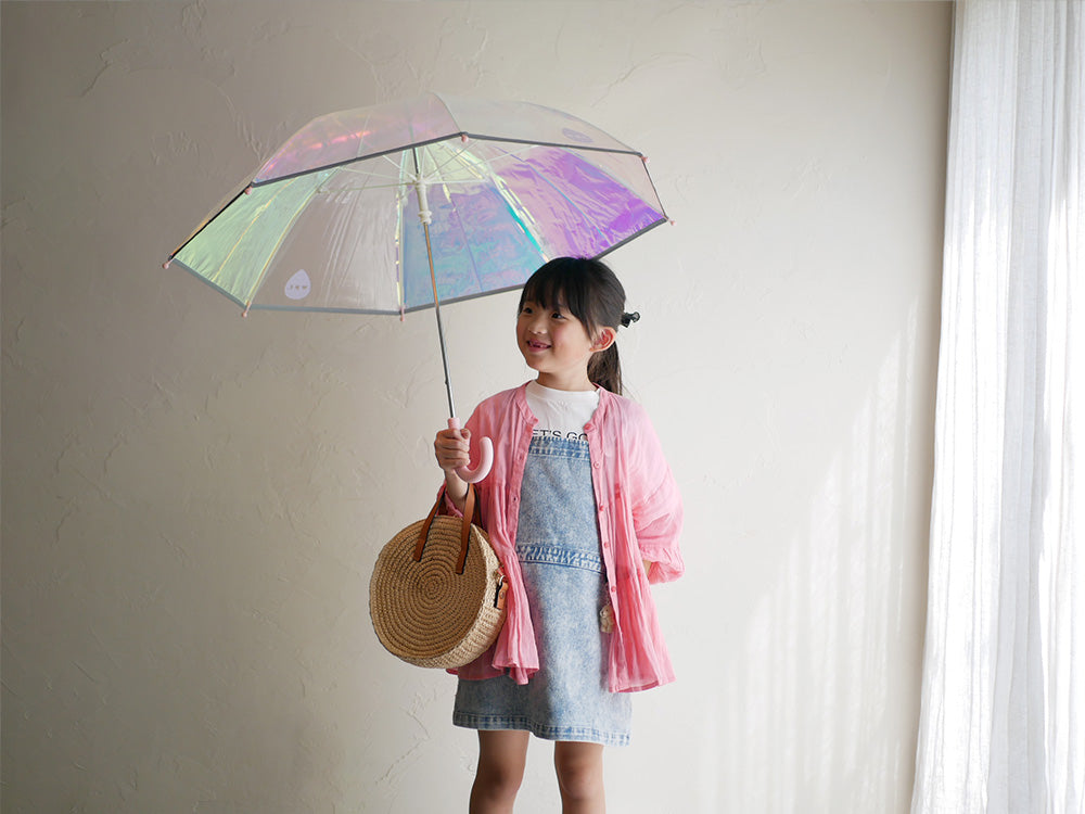 笑顔の幼児がピンクのシャイニーキッズアンブレラをさしている写真