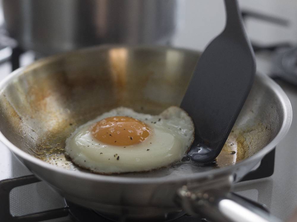 マーナのきほん ターナーを使ってフライパンで目玉焼きを調理しているキッチンの様子