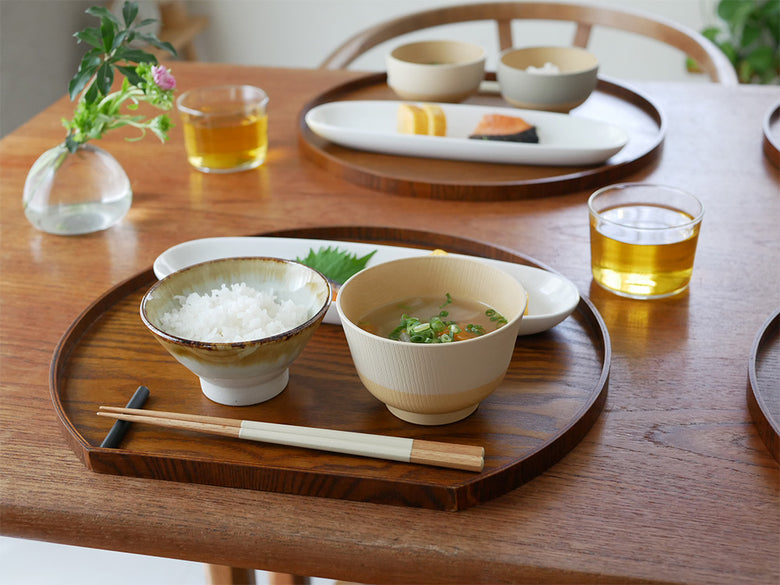 やさしい彩りシリーズの抗菌食器と木製箸が木のテーブルに美しく並べられたセット