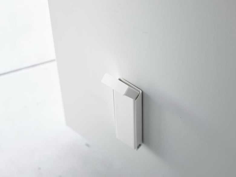 スチール製マグネット折り畳みドアストッパー「tower / タワー」の実物画像。シリコーン滑り止め付きで、磁石を使ってドアを固定するデザイン。