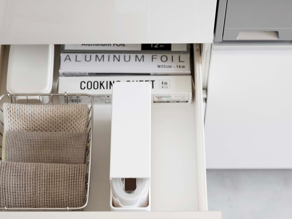 キッチンキャビネット内に設置されたスリムプラスチックバッグケース【タワー】。グレーとシルバーのABS樹脂製で、引き出しやカウンタートップと調和するモダンなデザイン。